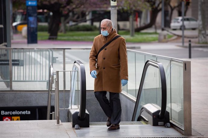 Un hombre protegido con una mascarilla y guantes de látex sale del metro durante el segundo día laborable del estado de alarma por el coronavirus, en Barcelona/Catalunya (España), a 17 de marzo de 2020.