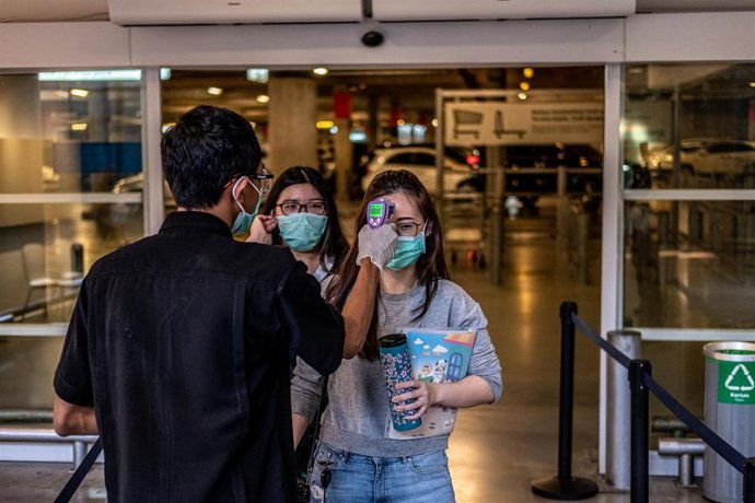 Un oficial controla la temperatura de dos muchchas a la entrada de un centro comercial de la provincia de Bantén, al oeste de la isla de Java (Indonesia).