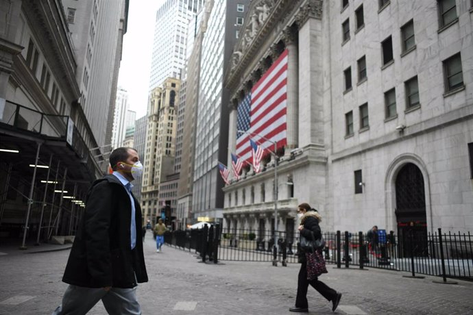 Un hombre con mascarilla atraviesa Wall Street