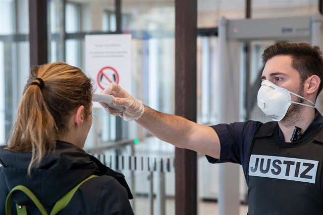 Un empleado de un tribunal de Nuremberg toma la temperatura a una visitante