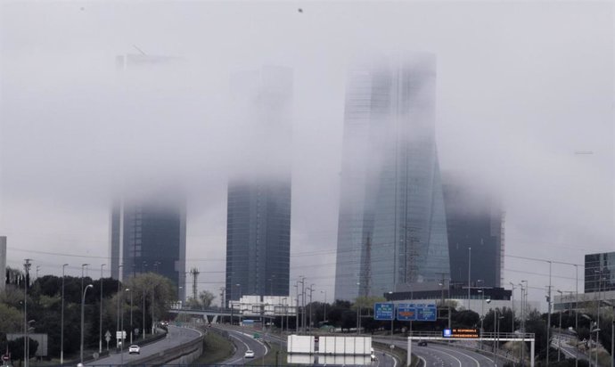 Las cuatro torres de Madrid con niebla y carretera vacía