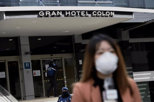 Una periodista cubierta con una mascarilla informa de la situación en la puerta del primer "hotel medicalizado", el Gran Hotel Colón