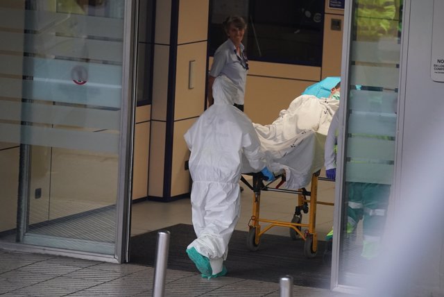 Un sanitario protegido con un traje y guantes de látex, empuja una camilla con una persona sobre ella en el Hospital Universitario Cruces, 19 de marzo de 2020.