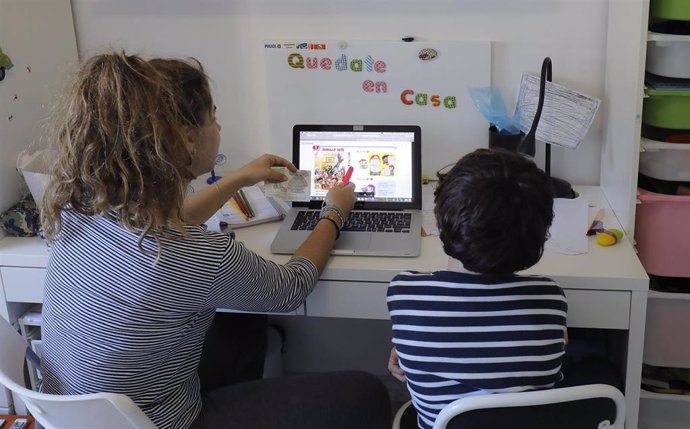 Una madre estudia con su hijo en su casa con la ayuda del televisor. Esta es una nueva forma forma de aprendizaje durante el confinamiento por el COVID-19. Sevilla a 27 de marzo del 2020
