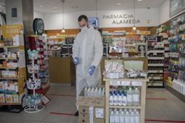 Imagen de una farmacia de Sevilla con un profesional ataviado con un equipo de protección. 