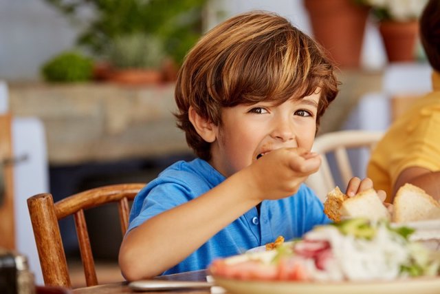 Portrait of boy eating food at table in house
