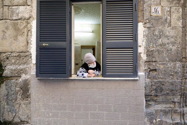 Una mujer con mascarilla en una ventana en Nápoles