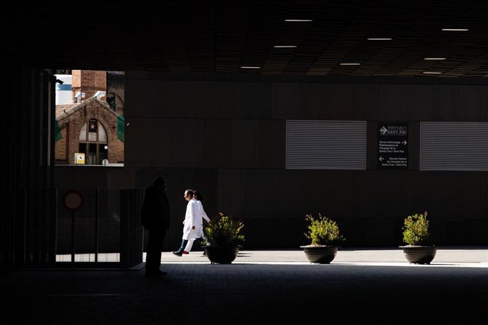 Personal médico pasa junto al Hospital Sant Pau durante el confinamiento
