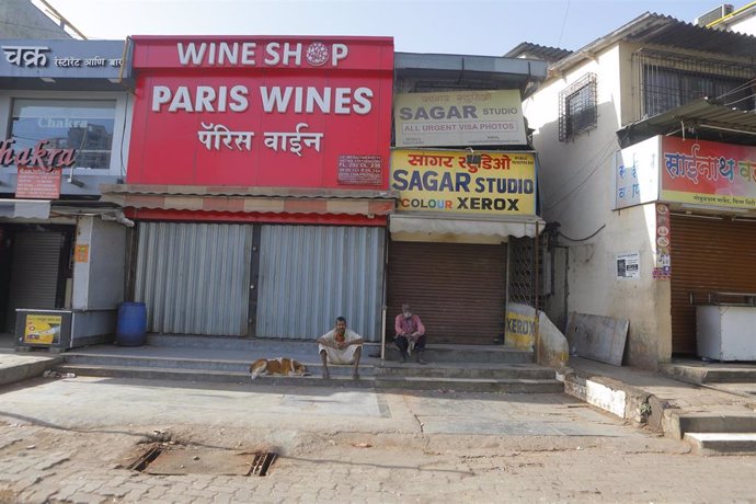 Dos ciudadanos sentados a las puertas de una tienda de vinos en Bombay.
