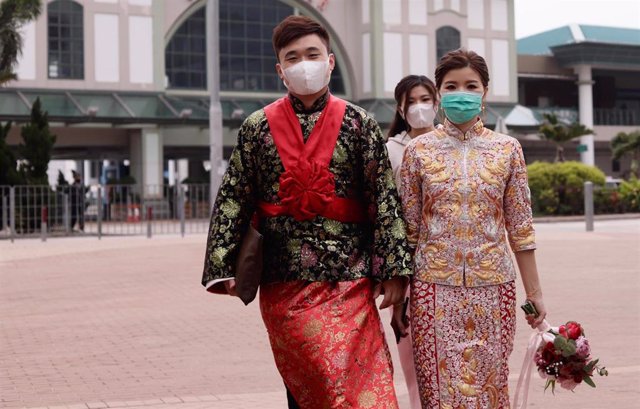 Una pareja, vestidos con trajes de boda tradicionales chinos, se protegen con máscaras faciales en medio de la pandemia de coronavirus en Hong Kong.  