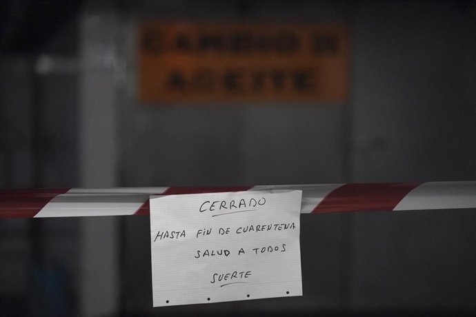 Una empresa mecánica que efectúa cambios de aceite advierte con un cartel que permanecerán cerrados hasta el fin de la cuarentena en la ciudad de Bilbao