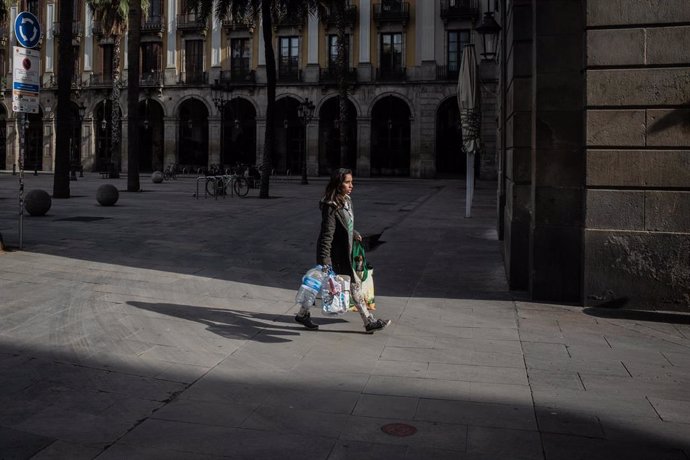 Una mujer anda con varias bolsas después de haber hecho la compra, durante el tercer día laborable del estado de alarma por coronavirus, en Barcelona/Catalunya (España) a 18 de marzo de 2020.