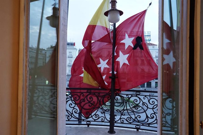 Vista desde el interior de las dependencias de la sede de la Comunidad de Madrid en la Puerta del Sol, con las banderas a media asta y un crespón negro en la bandera regional por los fallecidos por coronavirus, después de que la Comunidad de Madrid haya