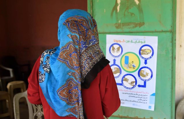 Imagen de una mujer en Sudán mirando un cartel informativo sobre el coronavirus. 