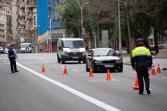 Dos Mossos d'Esquadra en un control de trnsit al carrer Balmes amb l'Avinguda Diagonal de Barcelona per vigilar que es compleixen les mesures de confinament el 31 de mar