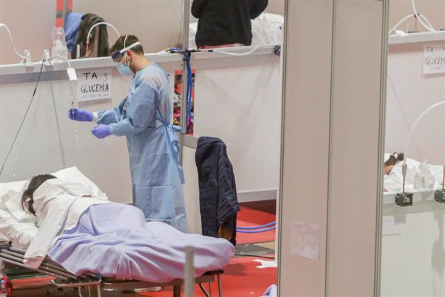 Un sanitario protegido con mascarilla atiende a una paciente ingresada por coronavirus en el Hospital de Campaña montado en el recinto madrileño de IFEMA, en Madrid, (España), a 3 abril de 2020.