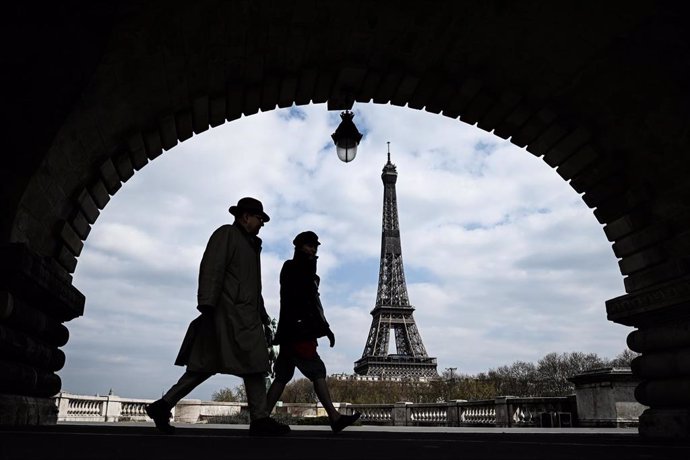 Transeúntes junto a la Torre Eiffel durante la crisis del coronavirus
