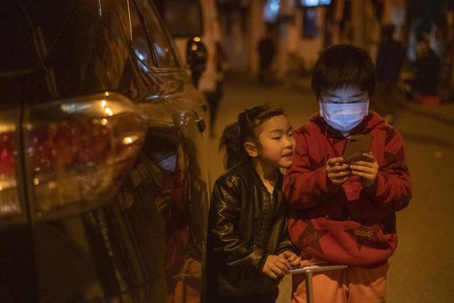 Dos niños se entretienen con un teléfono móvil en las calles de Shanghai.