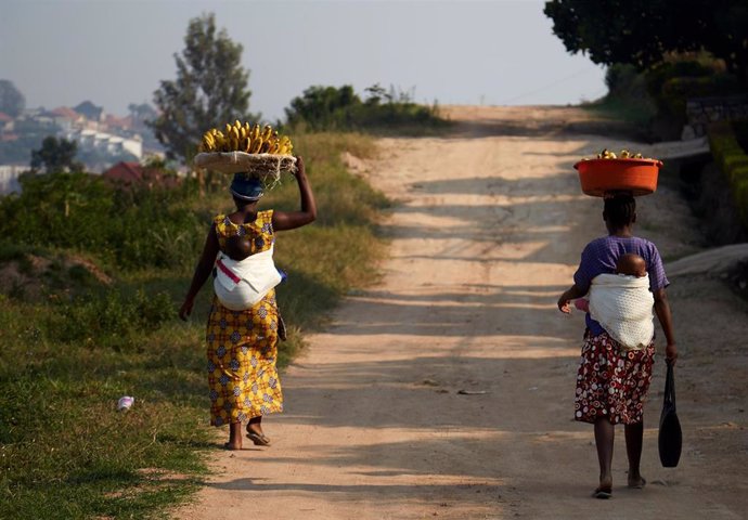 Dos mujeres caminan por un camino de Kigali, capital de Ruanda, portando sendas cestas de plátanos.
