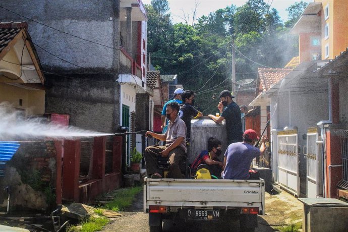 Residentes con mascarillas desinfectan edificios en Indonesia. 