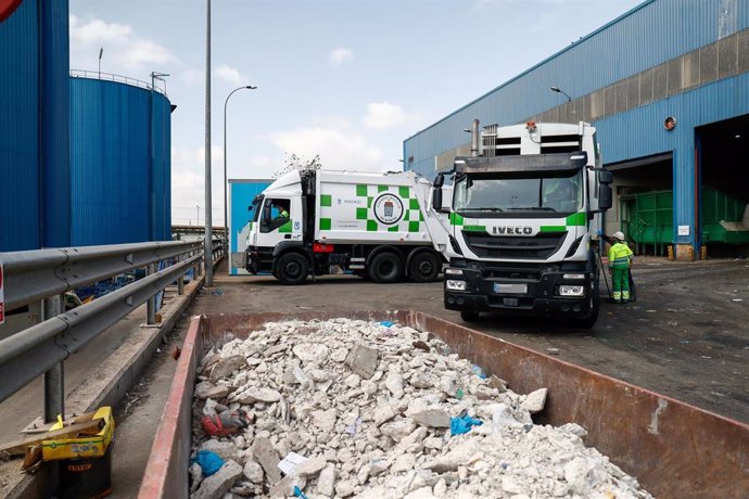 Un contenedor con escombros juntoa dos camiones de basura del Ayuntamiento de Madrid