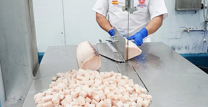 Un trabajador corta pescado congelado