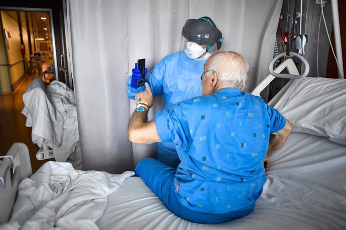 03 April 2020, Italy, Bergamo: A medic holds up a phone for a coronavirus patient to make a video call with a relative at the Papa Giovanni XXIII hospital. Photo: Claudio Furlan/LaPresse via ZUMA Press/dpa