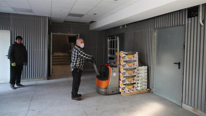 Un trabajador del Mercado de Maravillas prepara cajas de fruta en el reparto de más 1.000 kilos de fruta que los mercados municipales