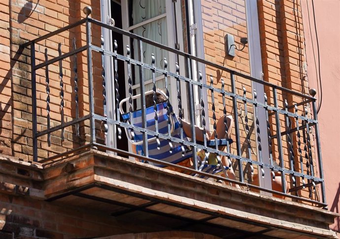 Un joven aprovecha su minúsculo balcón para tomar el sol en la tercera semana de confinamiento por el coronavirus COVID 19. Sevilla a 03 de abril del 2020