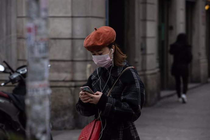 Una mujer con mascarilla en el Norte de Italia usando un smartphone durante el brote de coronavirus