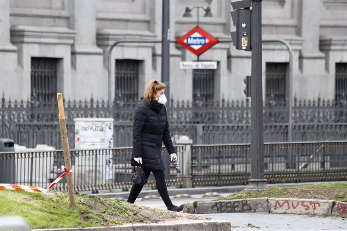 Una mujer con mascarilla pasea junto a la boca del metro de Banco de España durante el primer día de la cuarta semana de estado de alarma decretado por el Gobierno para combatir el coronavirus, en Madrid (España) a 6 de abril de 2020.