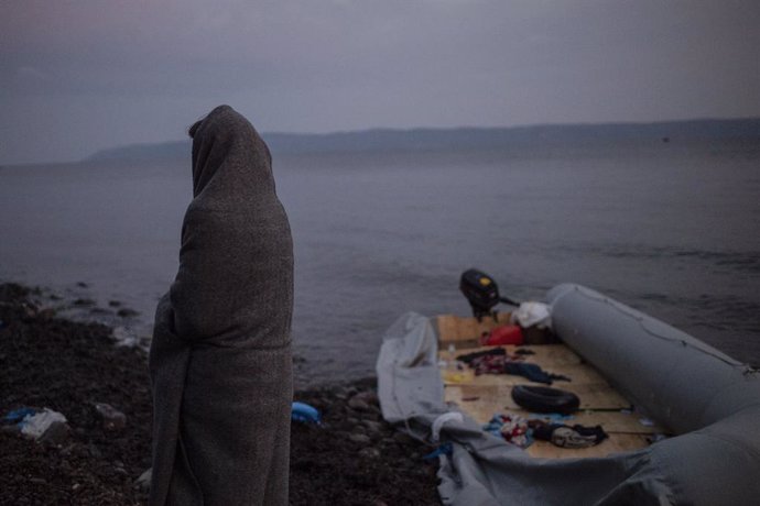 01 March 2020, Greece, Lesbos: A migrant wrapped in blankets stands next to a dinghy at the village of Skala Sikaminias, after crossing the Aegean Sigui from Turkey in a dinghy. Photo: Angelos Tzortzinis/dpa