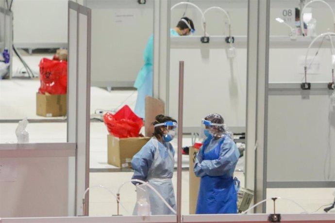 Dos sanitarios protegidos trabajan en el interior del Hospital temporal de la Comunidad de Madrid habilitado en Ifema