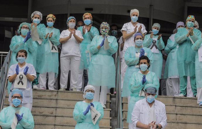 Sanitarios protegidos con mascarillas aplauden conmocionados tras el minuto de silencio en la entrada del Hospital Doctor Peset por la técnica de enfermería fallecida por coronavirus, en Valencia/Comunidad Valenciana (España) a 6 de abril de 2020.