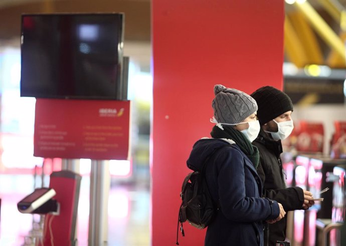 Dos pasajeros protegidos con mascarilla esperan en la Terminal 4 del Aeropuerto Adolfo Suárez Madrid-Barajas