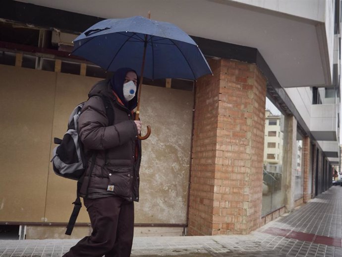 Un hombre con mascarilla camina protegiéndose con un paraguas por la lluvia  durante el Martes Santo y la cuarta semana del estado de alarma decretado por el Gobierno por la crisis del coronavirus, en Pamplona/Navarra (España) a 7 de abril de 2020.