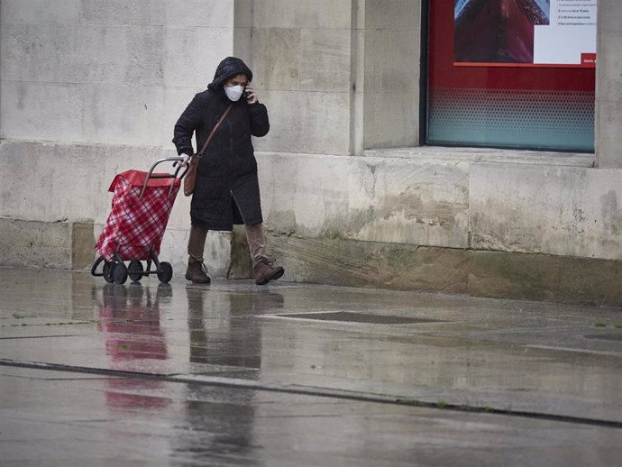 Una mujer con mascarilla camina bajo la lluvia con el carro de la compra durante el Martes Santo y la cuarta semana del estado de alarma decretado por el Gobierno por la crisis del coronavirus, en Pamplona/Navarra (España) a 7 de abril de 2020.