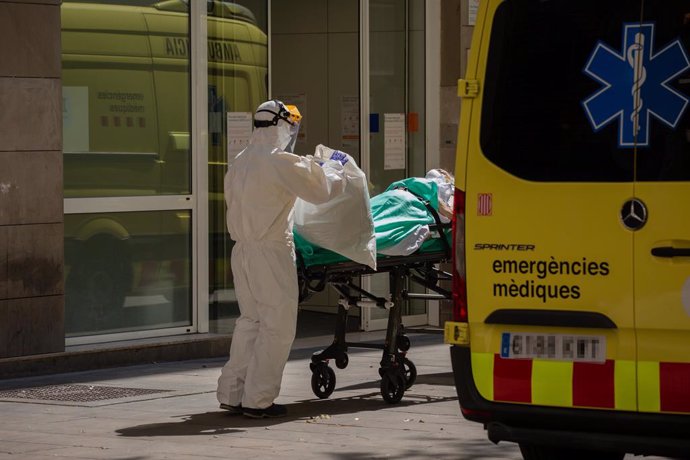 Un sanitari protegit amb un vestit transporta a una persona contagiada amb coronavirus en una llitera abans d'entrar en una ambulncia al Centre Pere Camps en el Raval, a Barcelona/Catalunya (Espanya) a 6 d'abril de 2020.
