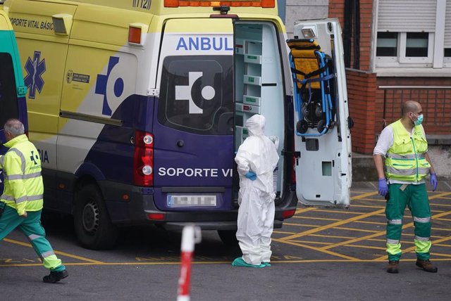 Varios sanitarios protegidos, uno con un traje y otro con mascarilla y guantes de látex, junto a una ambulancia en el Hospital Universitario Cruces, uno de los hospitales públicos vascos de referencia para infectados por coronavirus, en Bilbao/Euskadi