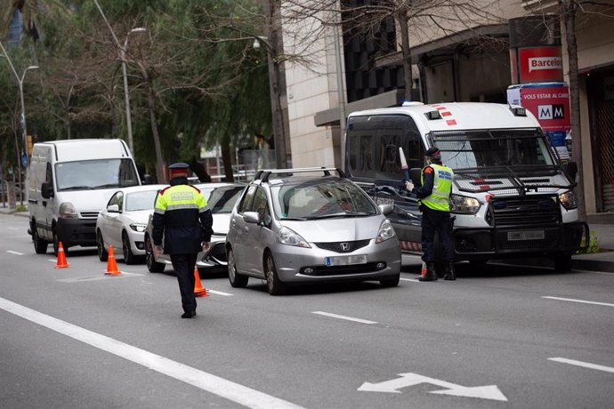 Dos Mossos d'Esquadra en un control de tráfico en la calle Balmes con la Avenida Diagonal de Barcelona para vigilar que se cumplen las medidas de confinamiento durante el segundo día de la entrada en vigor de la limitación total de movimientos salvo de 