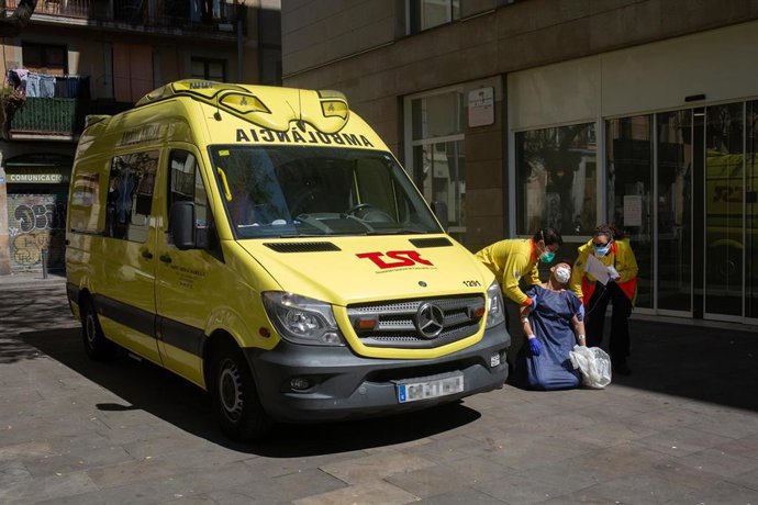 Dos sanitarios sujetan a un joven contagiado con coronavirus que se está desmayando antes de subirle a una ambulancia en el Centro de Emergencias de Atención Primaria Pere Camps en el Raval, durante el traslado de personas de colectivos vulnerables desd
