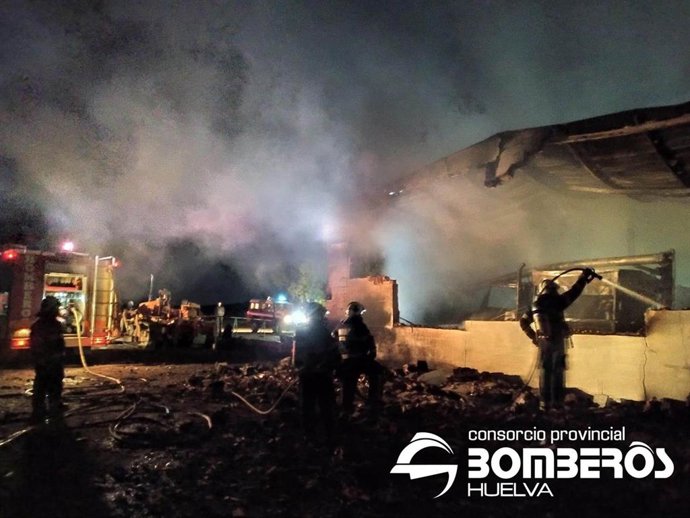 Bomberos tratan de sofocar el incendio en una nave de maquinaria de Encinasola