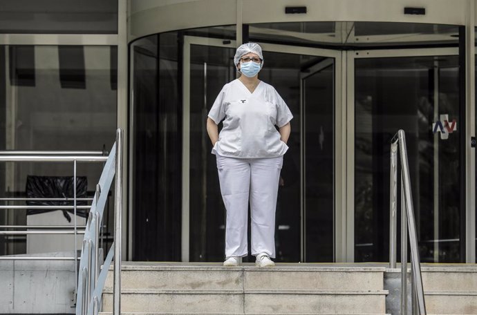 Sanitaria protegida con mascarilla y gorro durante el minuto de silencio en la entrada del Hospital Doctor Peset