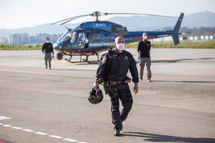 Tres agentes de los Mossos d'Esquadra al bajar de un helicóptero en el aeródromo de Sabadell tras realizar vuelos de reconocimiento en los que controlan que se esté cumpliendo el confinamiento, en Sabadell/Barcelona (Cataluña) a 8 de abril de 2020.