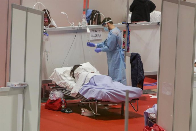 Un sanitario protegido con mascarilla atiende a una paciente ingresada por coronavirus en el Hospital de Campaña montado en el recinto madrileño de IFEMA, en Madrid, (España), a 3 abril de 2020.