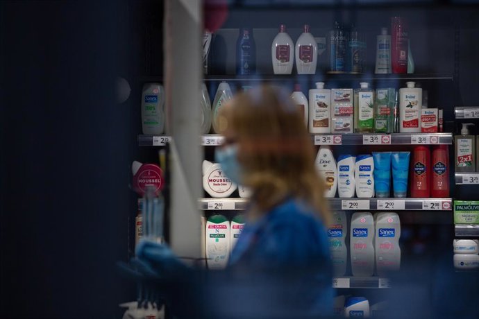 Una dona protegida amb mascarilla i guants treballa en una botiga durant el nov dia laborable des que es va decretar l'estat d'alarma al país a conseqüncia del coronavirus, a Barcelona/Catalunya (Espanya) a 26 de mar de 2020.