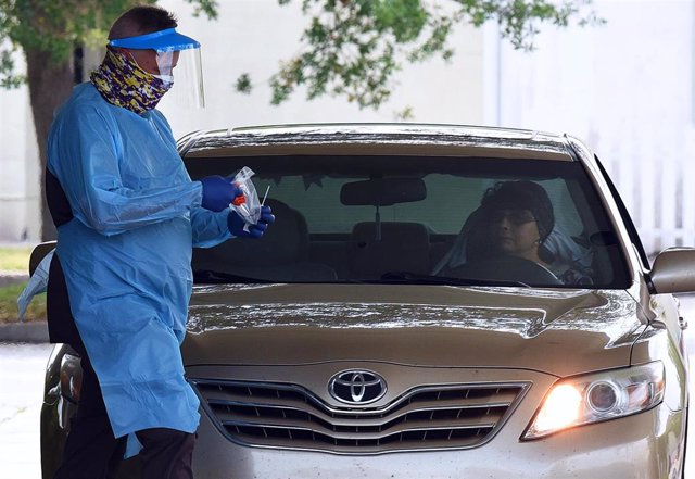 April 8, 2020 - Melbourne, Florida, United States - A healthcare worker wearing personal protection equipment prepares to administer a coronavirus test to a woman in a car on the second day of a drive-thru COVID-19 test collection facility operated by Omn