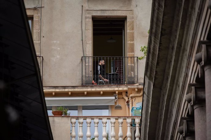 Un jove utilitza el seu ordinador porttil en la seva terrassa durant el segon dia laborable de l'estat d'alarma pel coronavirus, a Barcelona (Espanya), a 17 de mar de 2020.