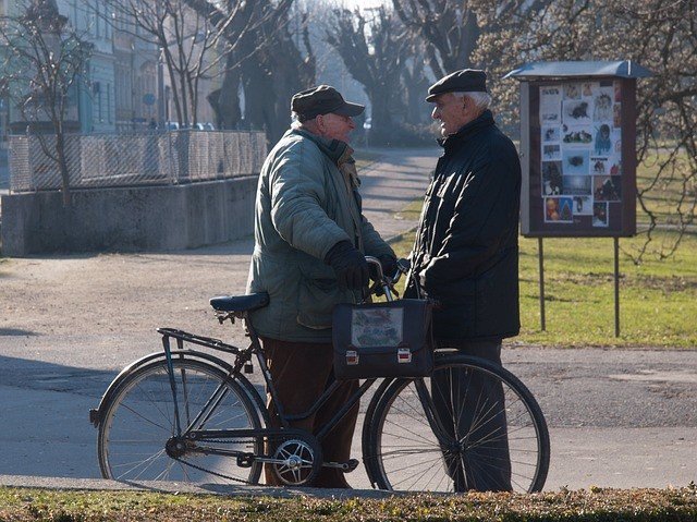 Dos hombres mayores hablando en la calle.