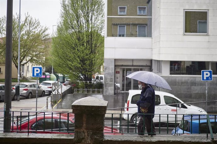 Un hombre con mascarilla camina protegiéndose con un paraguas por la lluvia  durante el Martes Santo y la cuarta semana del estado de alarma decretado por el Gobierno por la crisis del coronavirus, en Pamplona/Navarra (España) a 7 de abril de 2020.